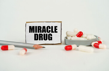 On a white background, medical capsules, a pencil and a cardboard plate with the inscription - MIRACLE DRUG