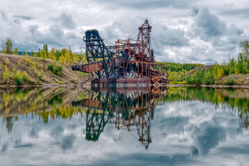Old rusty abandoned gold mining dredge in a pond in Alaska