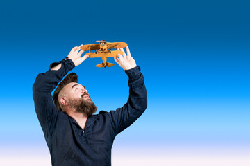 Mature man playing with a toy airplane. Bearded man with a toy plane. Symbol of dreams and...