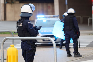 Policjantka wieczorem przy radiowozie na sygnałach. Z pałką. © FotoDax