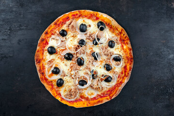 Traditional Italian pizza al tonno with tuna, onion and olives served as top view on an old rustic board with text free space