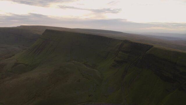 Aerial view of a lake at the foot of large cliffs (Llyn y Fan Fach). Idyllic Brecon beacons national park llyn y fan fach mountain range aerial.  Brecon Beacons National Park in Wales. 