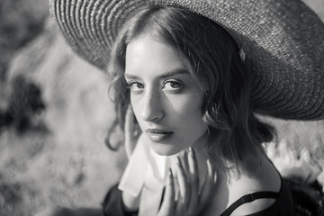 Black and white portrait of stylish girl in straw hat posing on a background of the city.