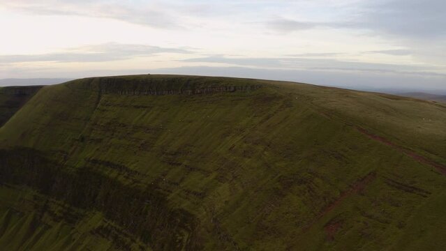 Aerial view of a lake at the foot of large cliffs (Llyn y Fan Fach). Idyllic Brecon beacons national park llyn y fan fach mountain range aerial.  Brecon Beacons National Park in Wales. 