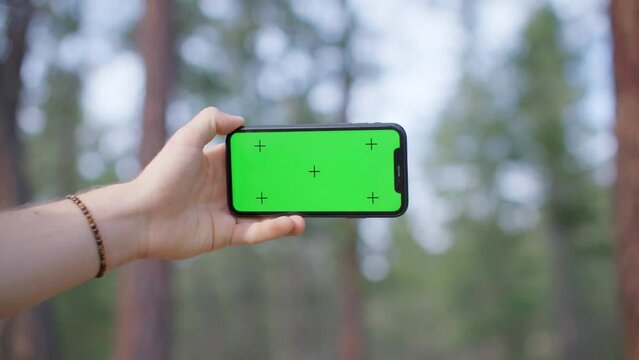 Man holding phone in forest, green screen mockup, iphone, landscape