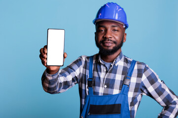 Construction worker in blue uniform work coveralls holds cell phone with empty screen for...