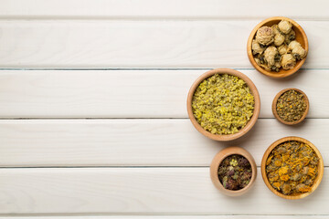 Different herbs in bowls on wooden background, top view