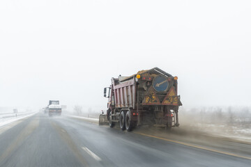Snowplow truck removing dirty snow from city street or highway after heavy snowfalls. Traffic road...