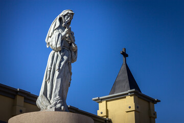Beautiful statue of Santa Rita de Cassia, with church tower and blue sky in the background