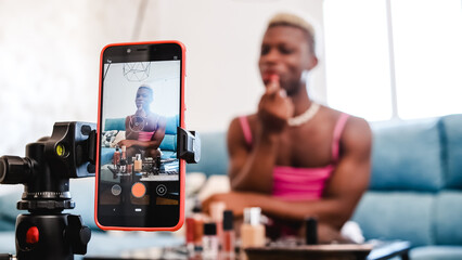 Transgender beauty blogger applying makeup to mobile phone camera