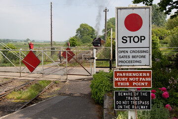 A steam train approaching level crossing.