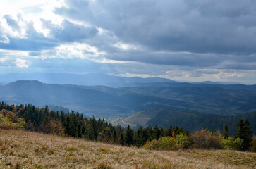 Beautiful autumn landscape with yellow and red trees, high mountains and cloudy sky. Carpathian Mountains, Ukraine