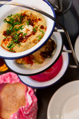 Appetizing set of tree traditional Balkan appetizers Mezze trio consisting of beet hummus, baked cauliflower and corn polenta with bacon and cream cheese served with freshly baked pita in cloth bag..