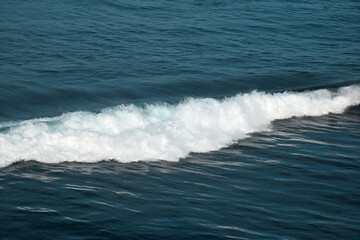 Fototapeta premium The waves crashing in the ocean, with a bluish tint at Drini Beach, Gunungkidul, Yogyakarta