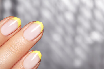 Hands with bright yellow french manicure on geometric background. Nails art design. Close-up of...