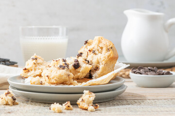 Chocolate chip muffins on a baking rack and glasses of milk on a white kitchen countertop.  Morning breakfast table