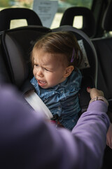 one small caucasian girl female toddler sit in the car safety seat cry