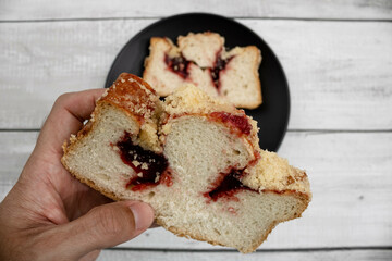 Slices of traditional German red berry cuca in the hands of a man with a black plate. A delicacy from the Silesian region between Poland and Germany quite popular for breakfast and afternoon.