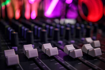 Close up of sliders on mixer in music production studio - neon background