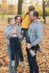 Outdoor portrait of a family, young father and mother with preschooler boy and toddler girl posing in the forest. Autumn forest. Outdoor lifestyle. Healthy