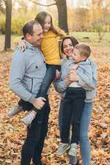 Mother and father walking with their kids in the park and enjoying the beautiful autumn nature. Family holiday and togetherness. Healthy activity. Parent, child