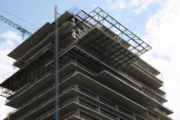 Obraz premium Multistory building under construction against cloudy sky, low angle view