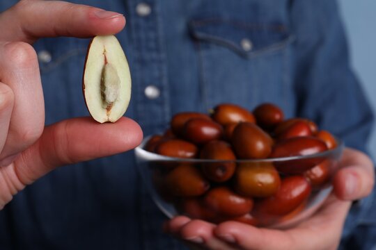 Woman holding half of fresh Ziziphus jujuba fruit, closeup