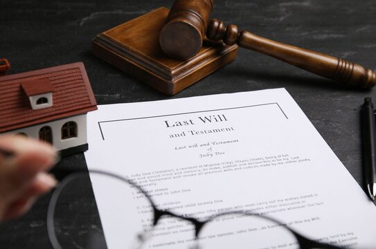 Last will and testament near house model, gavel on black table
