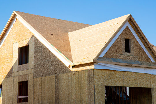 A residential house construction project showing plywood roof and dormer sheathing and oriented strand board on the exterior walls