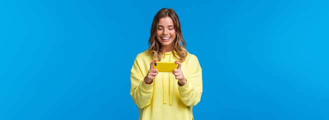 Time to relax on lunch break. Carefree good-looking hipster girl in yellow hoodie using mobile...