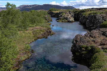Clouds reflected in glacial water filling a fissure between tectonic plates in Thingvellir National Park, Iceland