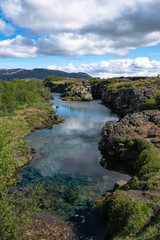 Naklejka na ściany i meble Clouds reflected in glacial water filling a fissure between tectonic plates in Thingvellir National Park, Iceland