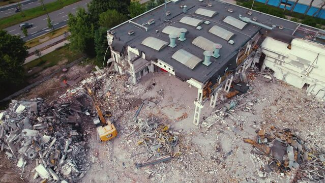 Heavy machinery, an excavator with hydraulic shears destroying an old building. Demolition construction work in Warsaw, Poland. Drone aerial view. High quality 4k footage