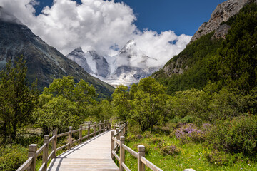 Fototapeta na wymiar Beautiful sunny day with mt. Chenrezig and wooden walkway in Yading national level reserve, Daocheng, Sichuan Province, China.