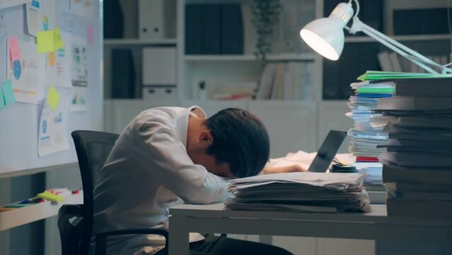 Exhausted Asian young businessman worker working on table in office.