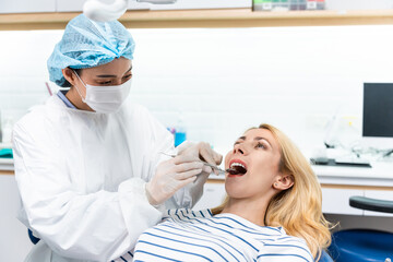 Female dentist examine tooth to Caucasian girl at dental health clinic. 
