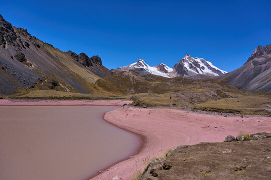 Paisaje natural de monte nevado con arena color rosa y cielo celeste en los andes peruanos 