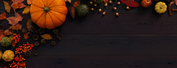Seasonal Wallpaper, with Autumn Leaves, Pumpkins and Berries on a Dark wood Surface. Thanksgiving Concept with space for text.