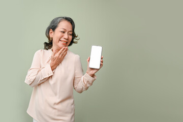 Cheerful and surprised 60s aged-asian woman palm touching chin, holding a smartphone