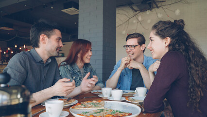 Close friends are sharing funny stories gesturing and laughing while having lunch in modern local...