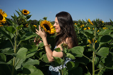 Woman smiling and smelling sunflower in a plantation