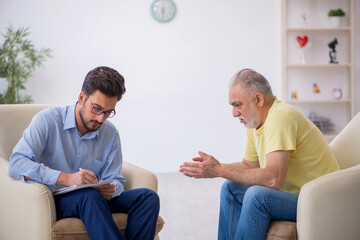 Obraz premium Old man visiting young male psychotherapist