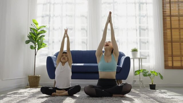 Portrait of young asian mother  daughter prepare for stretching post in yoga meditation. Mom and little girl toddler yoga exercise on yoga mat at home. Together lifestyle, Mother's Day concept