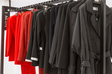Obraz premium Stylish bright women's clothing on hangers in the store. Fashionable jackets, trousers and dresses.
