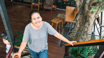 Happy Asian young woman standing in the coffee shop. One female only enjoying at the cafe in the city. Lady girl while relaxing outside the restaurant.