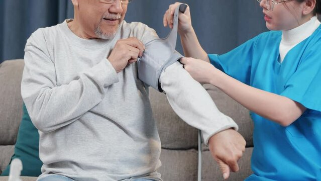 Asian nurse visit patient senior man at home she measuring arterial blood pressure on arm in living room, Doctor woman examine do checking old man client heart rate with pulsimeter monitor, Healthcare