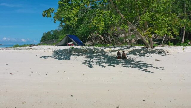 aerial of young couple on remote white sand tropical island beach in belitung indonesia