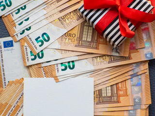 Blank sheet with copy space on the background of fifty euros banknotes with gift box. Set of European Union money. Enterprise capital investment, finance, savings, buying gifts, spending money concept