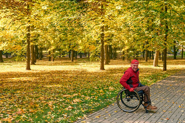 A photographer in wheelchair smiling and posing for camera in autumn park