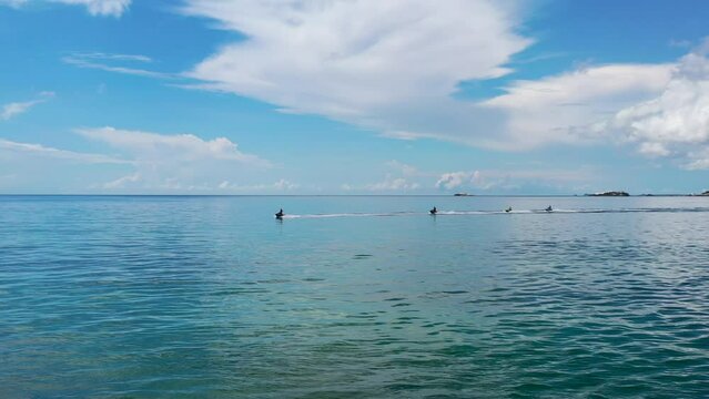 aerial of tourists on jet skis riding in tropical blue water on sunny summer day in belitung indonesia